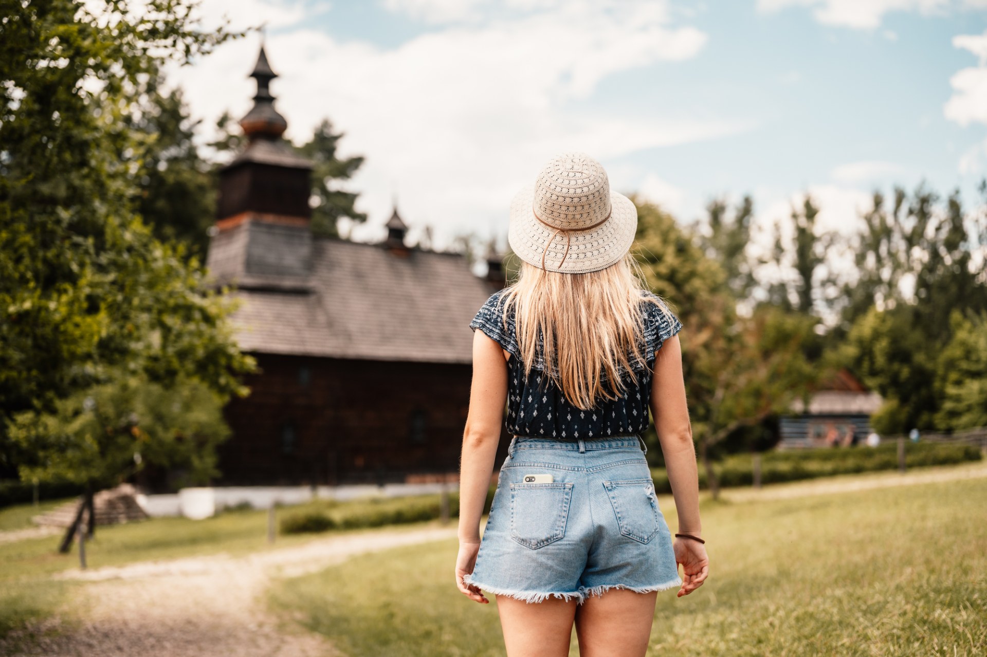 Junge Frau geht durch das Freilichtmuseum in Stará Ľubovňa zu einer Holzkirche